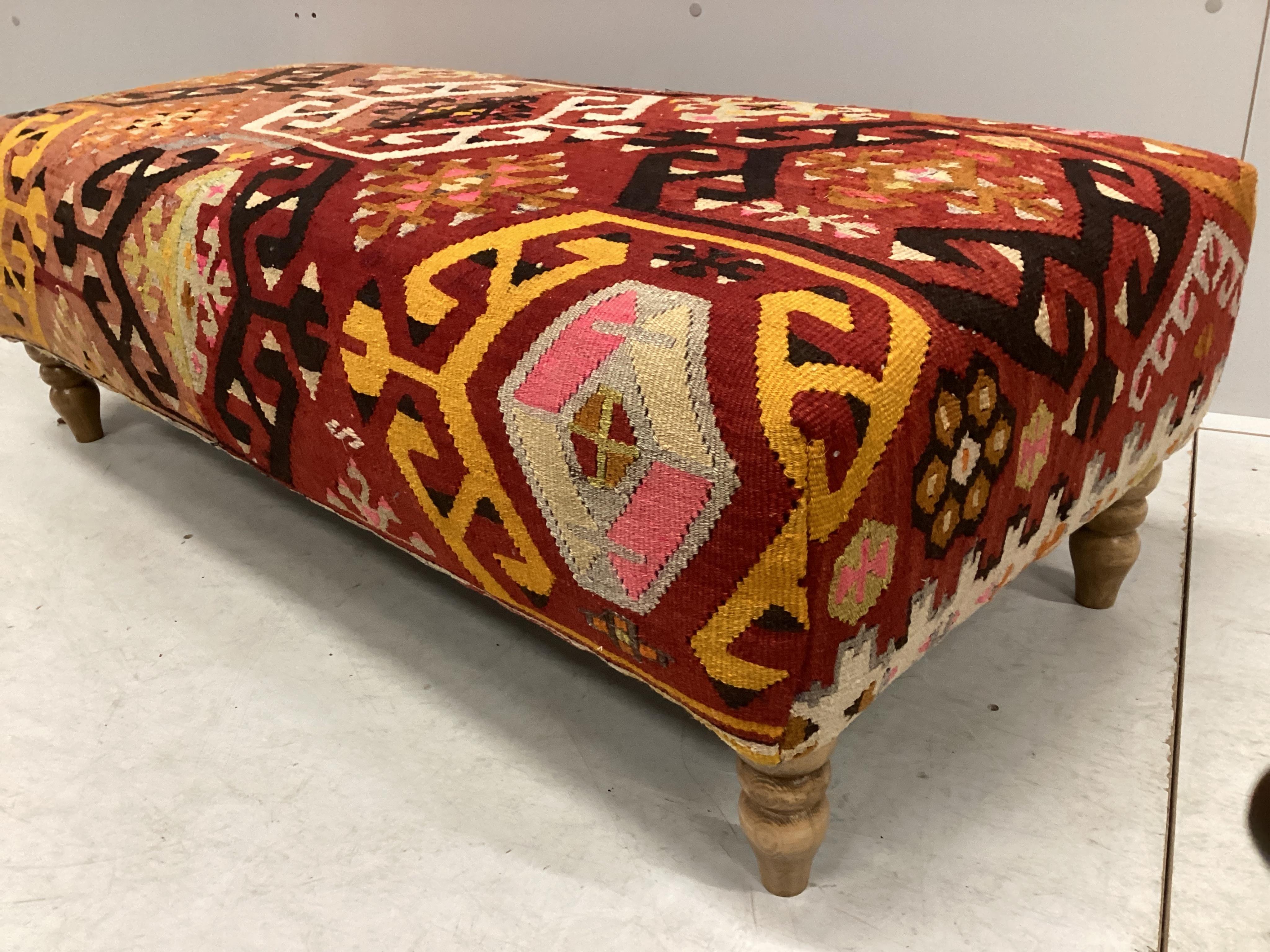 A large contemporary rectangular footstool with antique polychrome Kilim upholstery on turned beech feet, width 126cm, depth 58cm, height 40cm. Condition - good